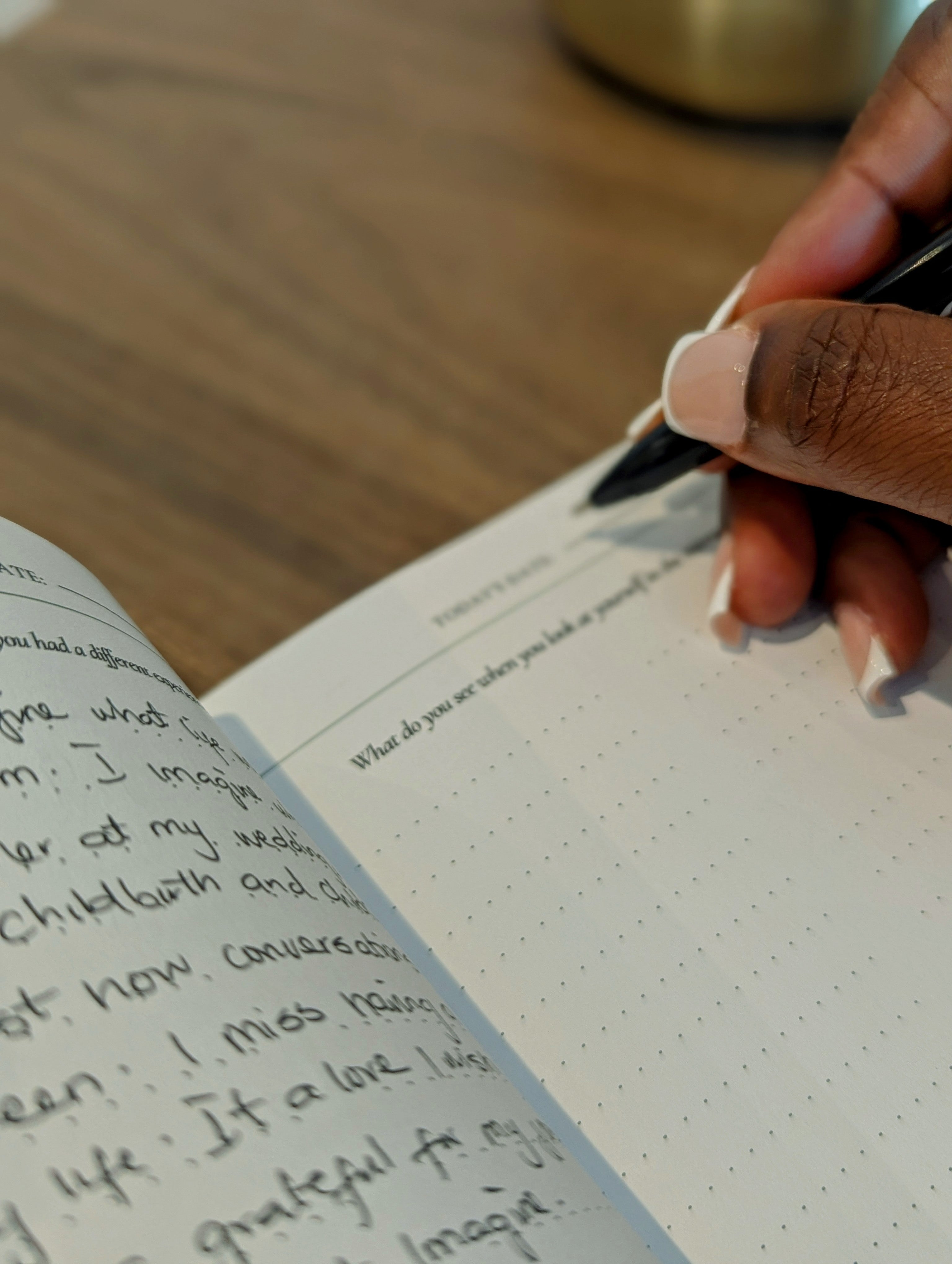 Yemi Ayodeji holding a pen over the unveiled journal writing on a wooden surface